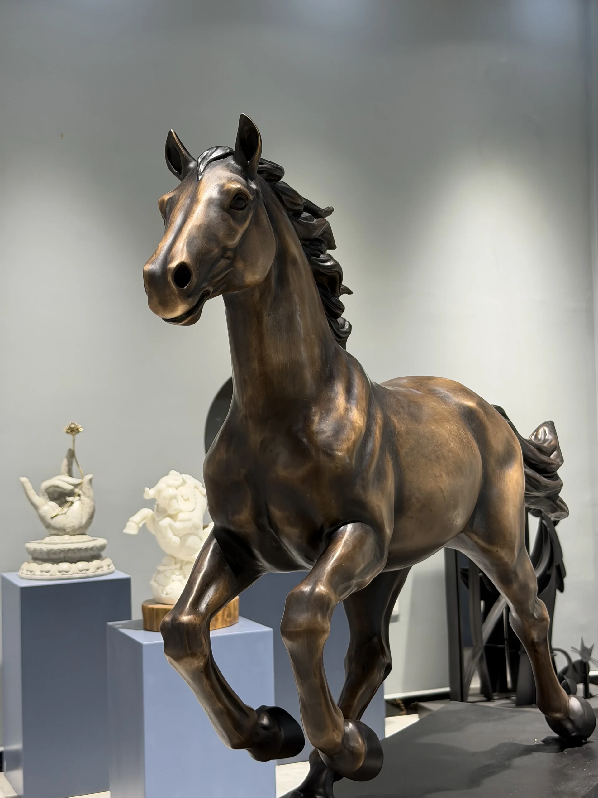Full-body view of a finished bronze horse sculpture with dark brown patina in a showroom