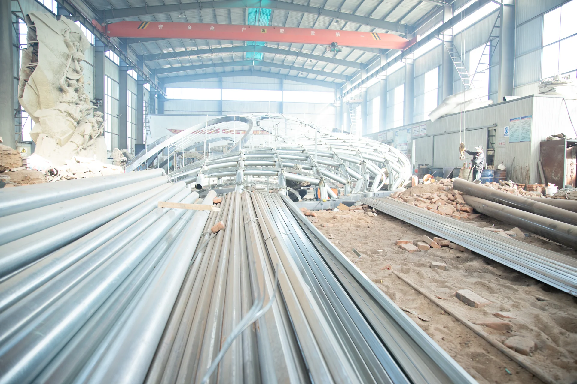 Sculpture fabrication workshop with a large metal armature under an overhead crane