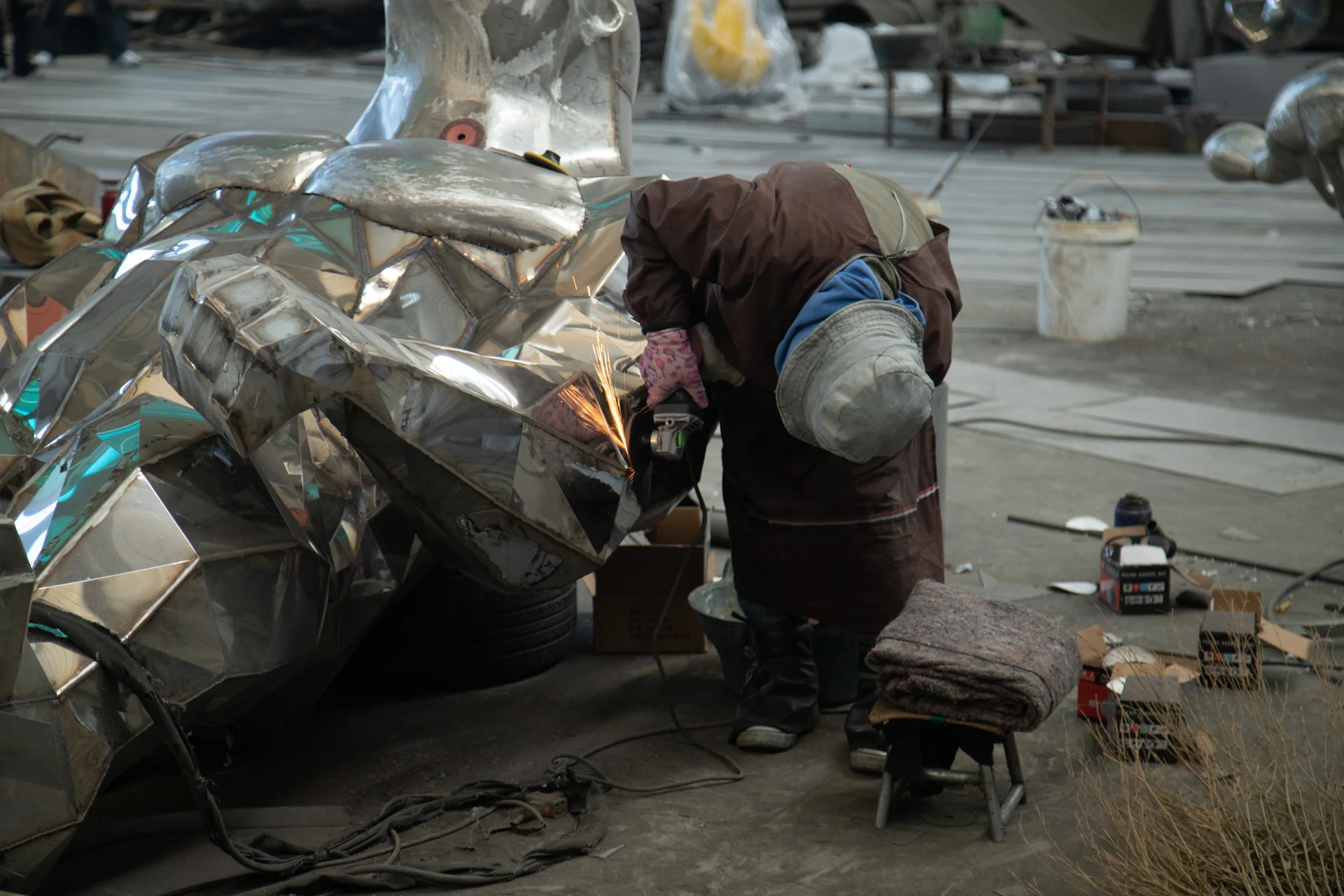 Worker grinding the welded surface of a stainless steel sculpture