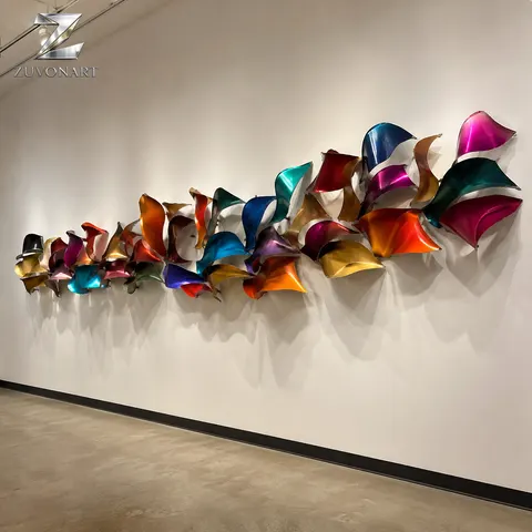 A horizontal band of colored folded planes creates a rhythmic wall-mounted ribbon.